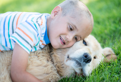 Criança careca abraçando cachorro