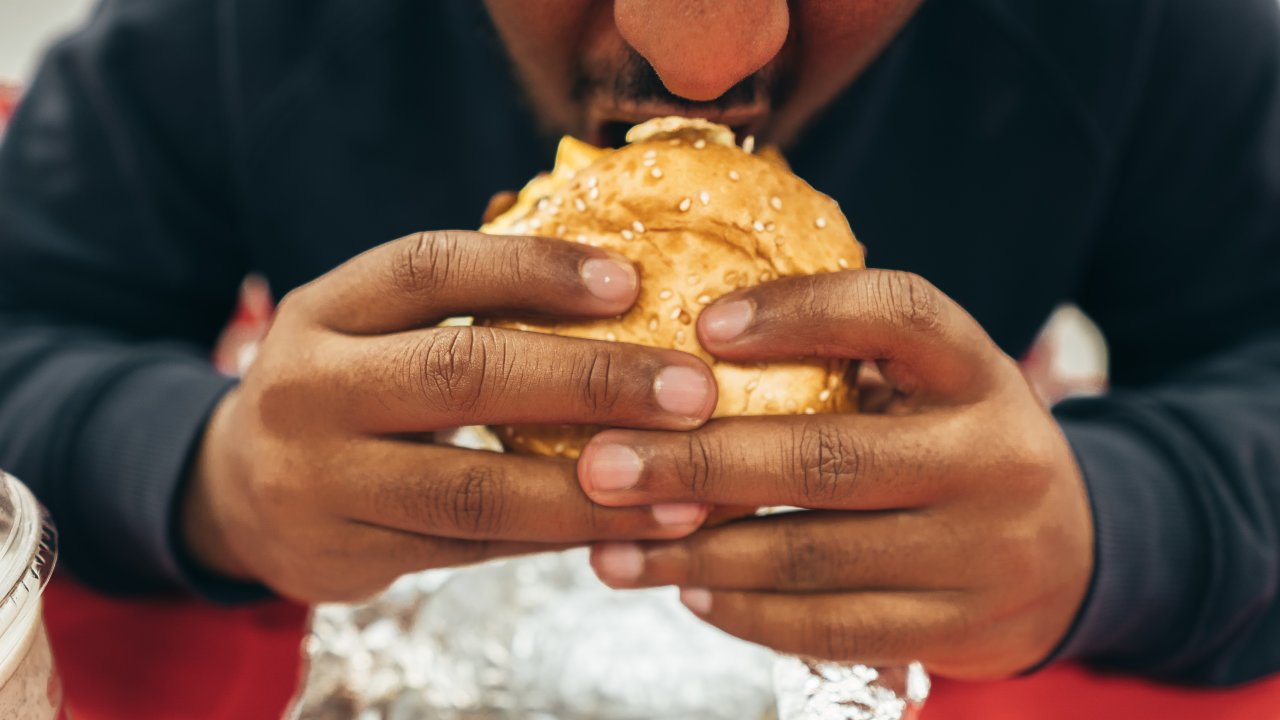 homem comendo um hambúrguer
