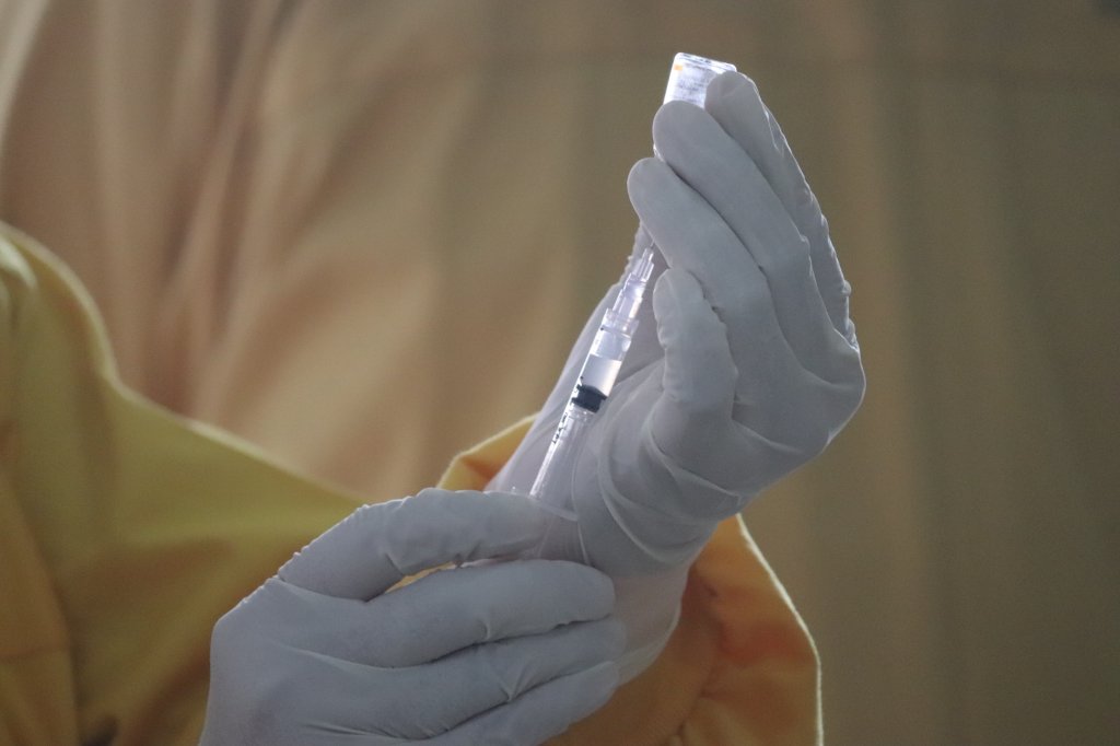 Foto de mão com luva segurando vacina da aids