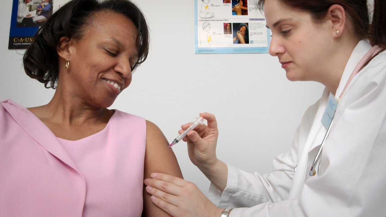 Foto de mulher recebendo a vacina da gripe, em referência à campanha nacional de vacinação contra a gripe de 2021