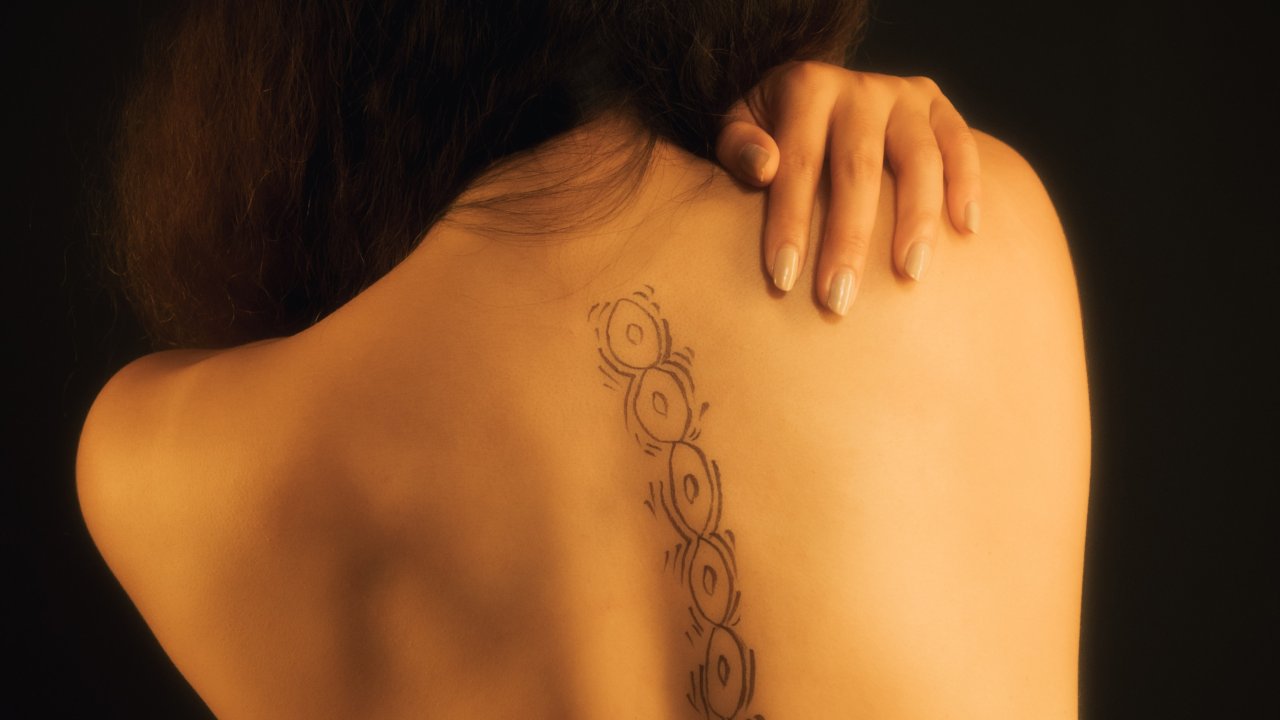 Mulher com desenho de vértebras nas costas, simbolizando a quiropraxia