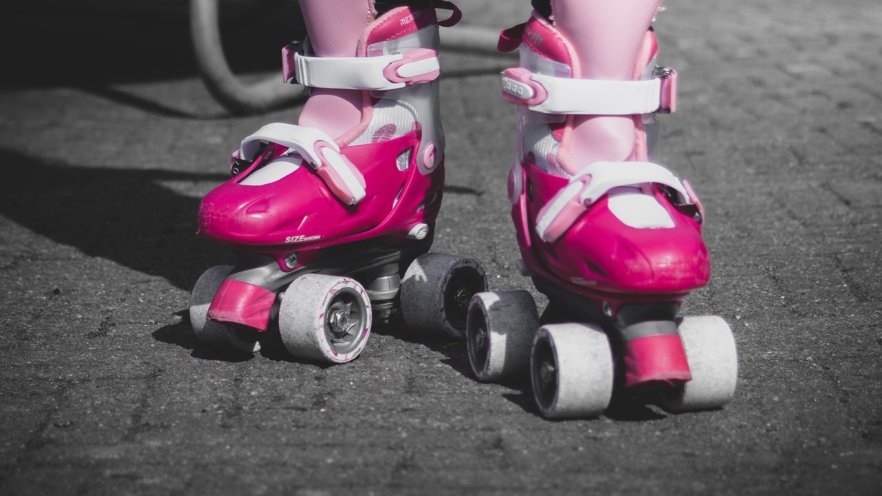 Foto do joelho pra baixo de uma criança usando patins rosas