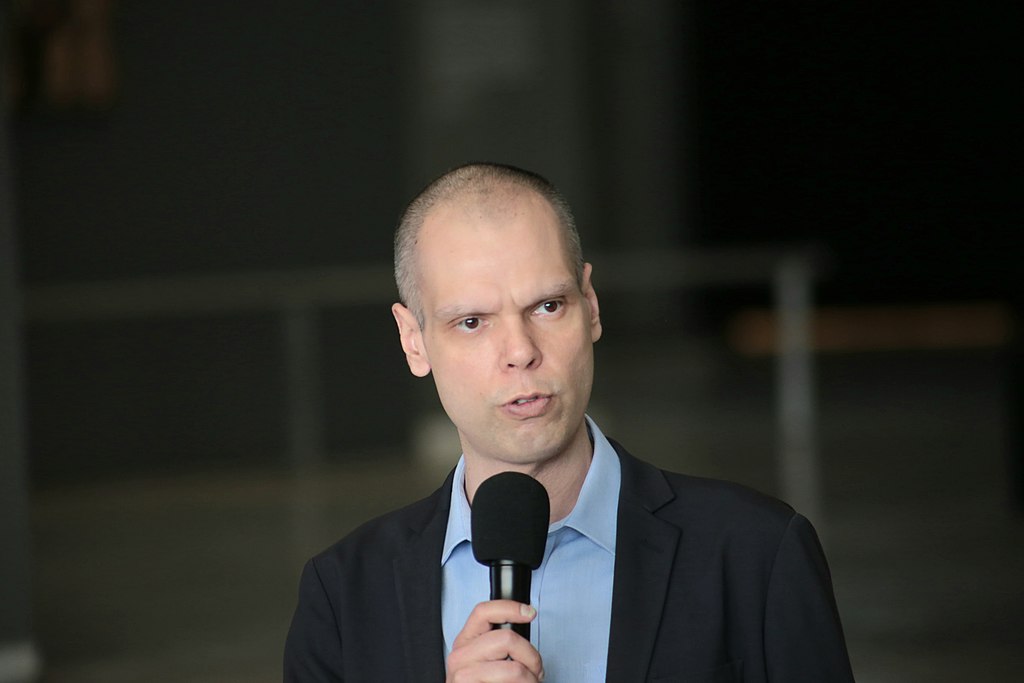 Foto do prefeito Bruno Covas, que tem câncer, segurando microfone durante coletiva de imprensa