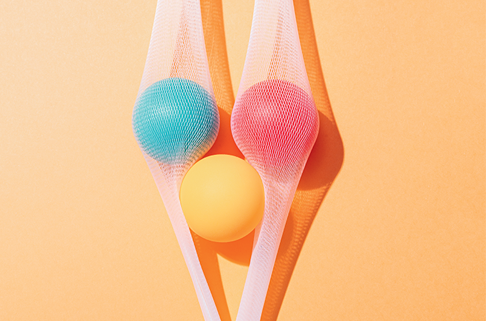 Foto de três bolas de pingue pongue, duas delas cobertas por uma fina rede.