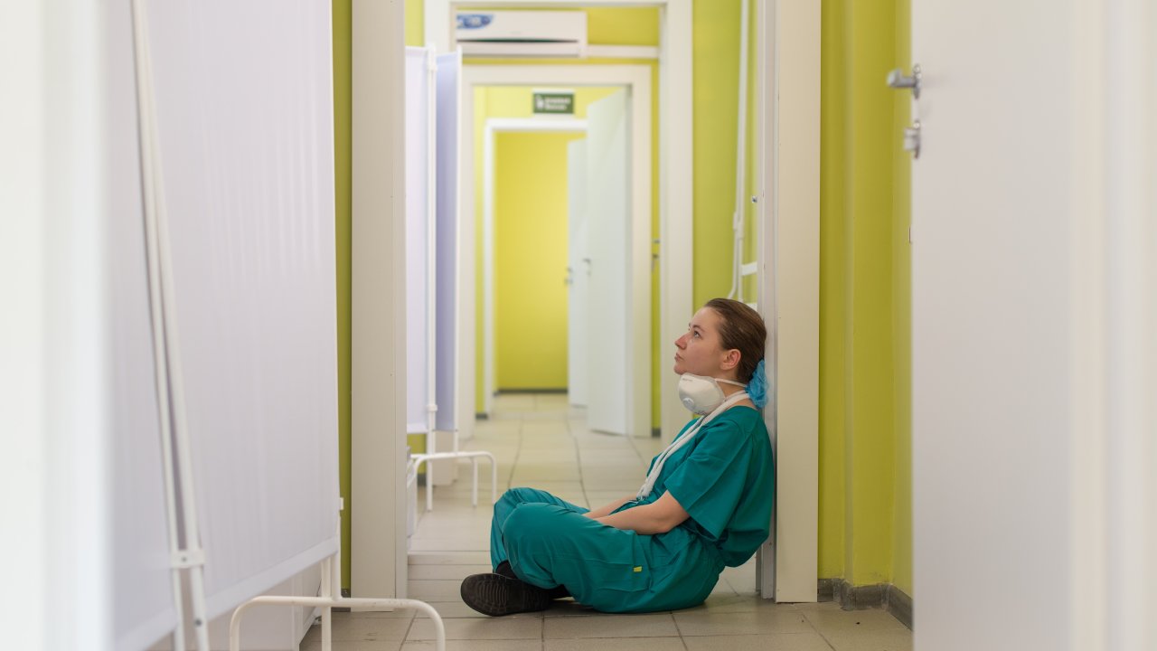 Foto de enfermeira sentada no chão de um hospital