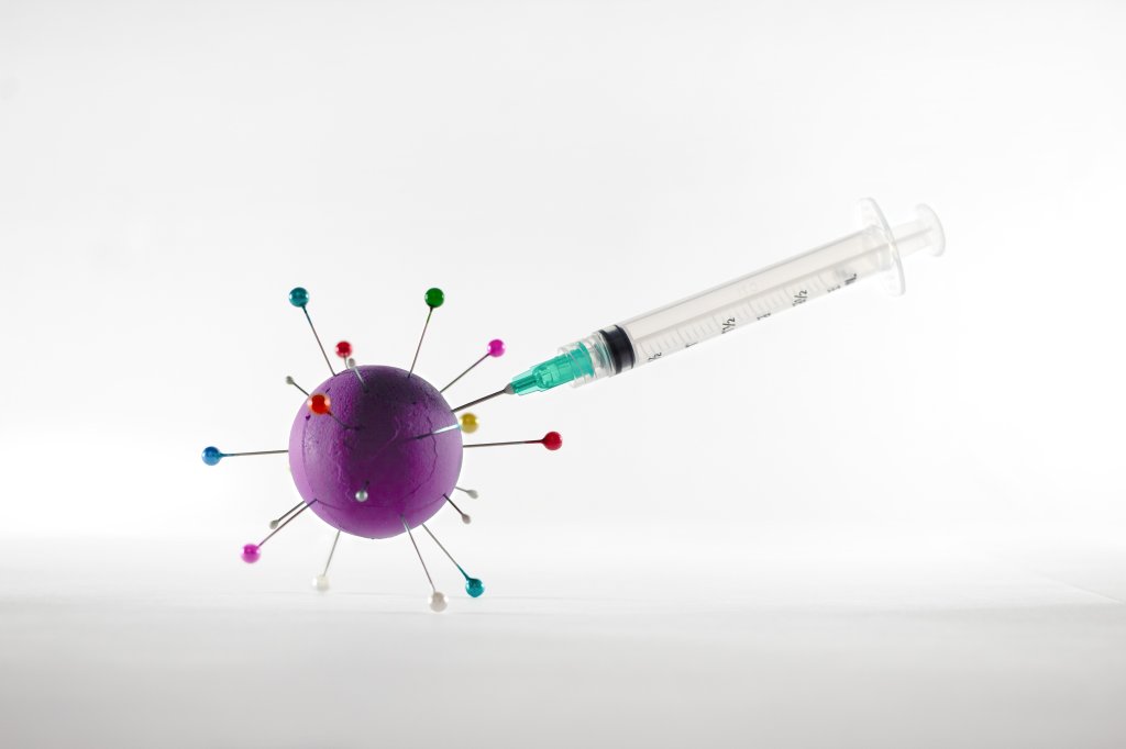 Seringa de vacina sendo espetada em modelo de coronavírus