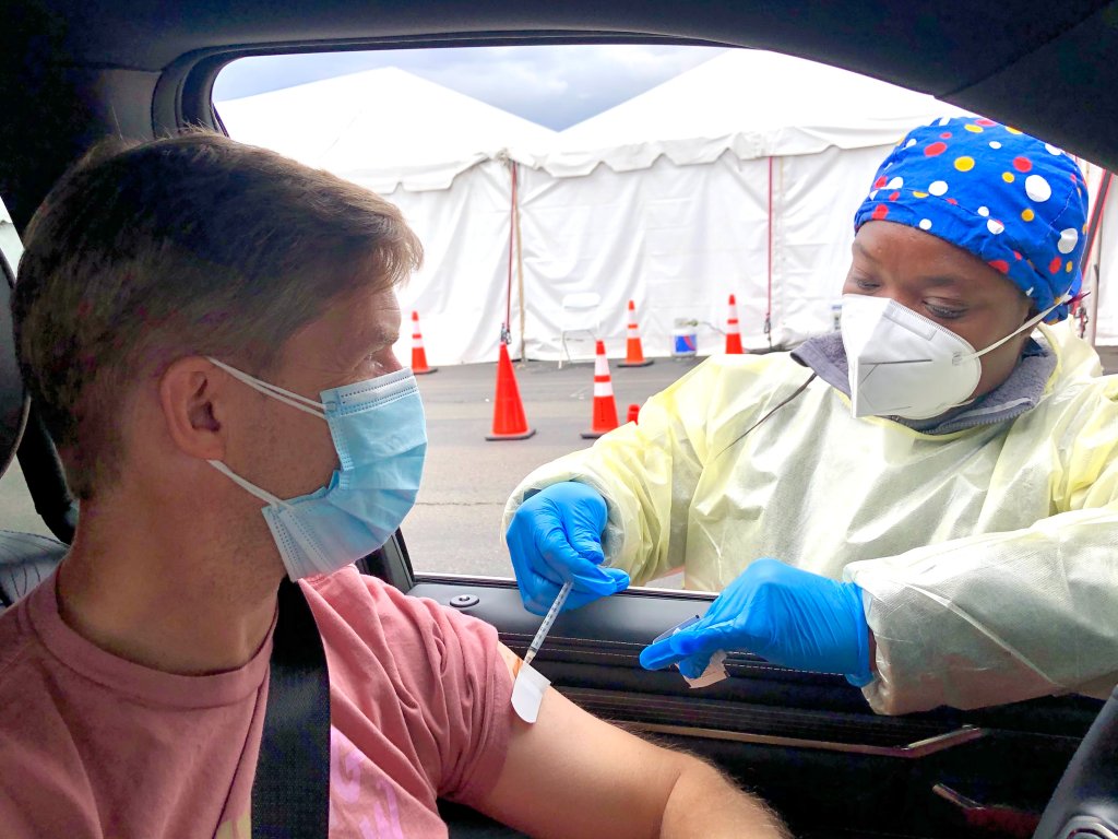 Foto de pessoa recebendo vacina da Covid-19 dentro do carro