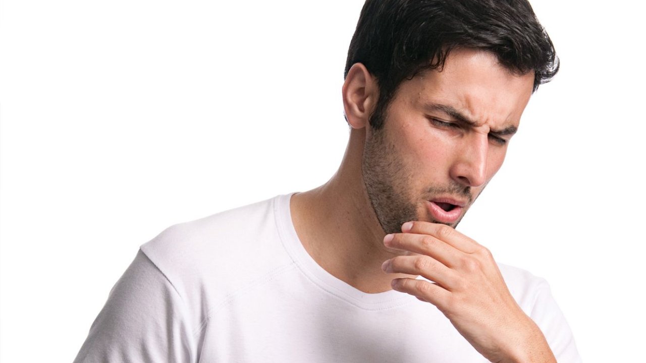 Foto de homem tossindo, um sintoma da tuberculose