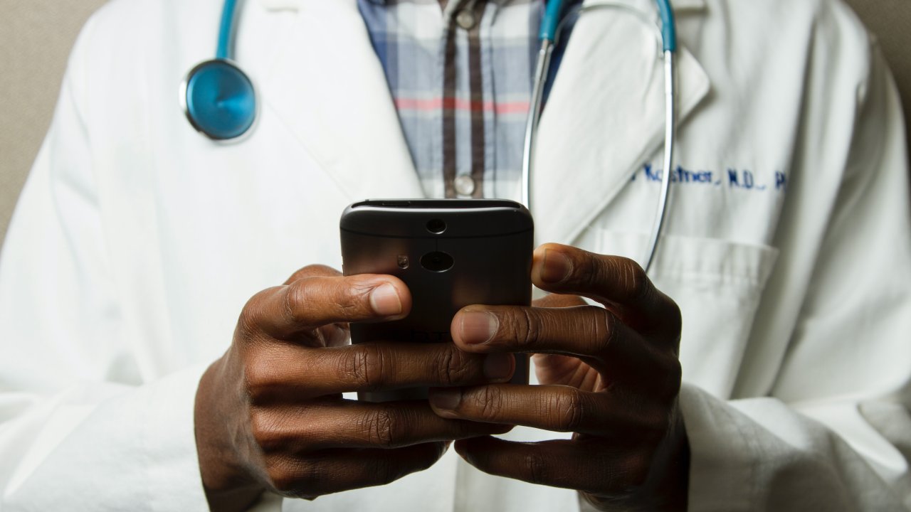 Foto de pessoa com jaleco de médico usando celular
