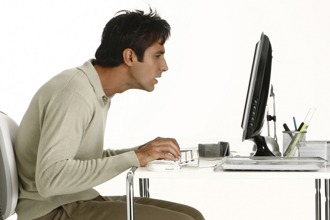 foto de homem trabalhando encurvado num computador