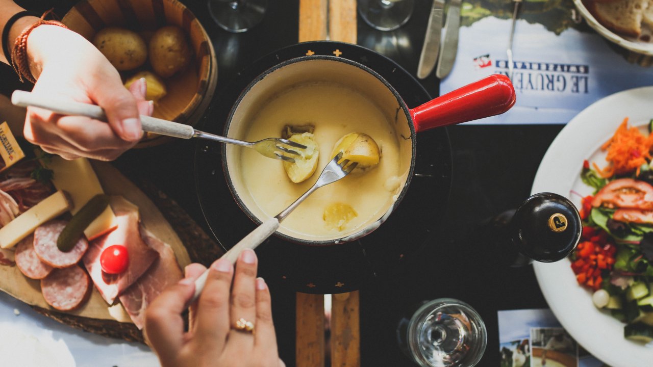 pessoas colocando batatas em uma panela de fondue