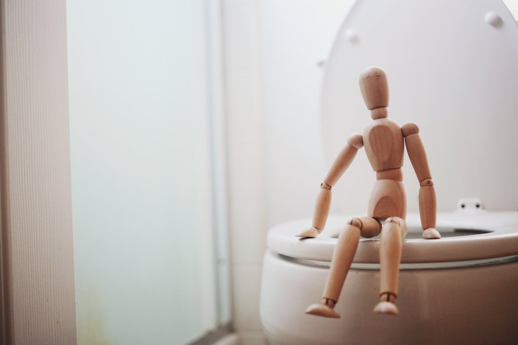 boneco sentado em um vaso sanitário