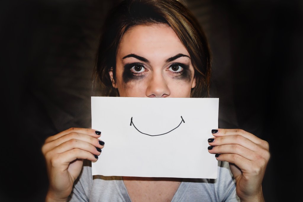 mulher com olhos borrados segurando um desenho de sorriso