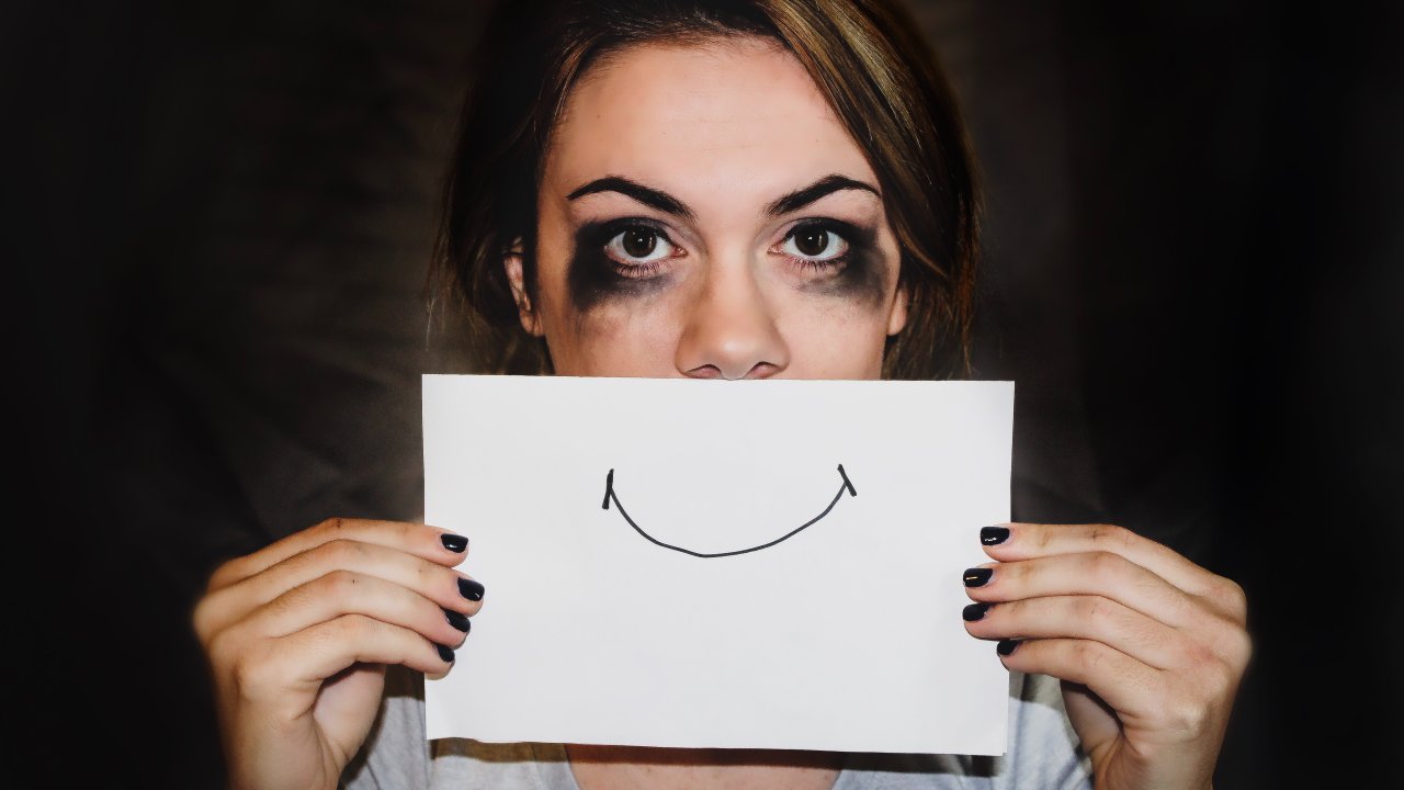 mulher com olhos borrados segurando um desenho de sorriso