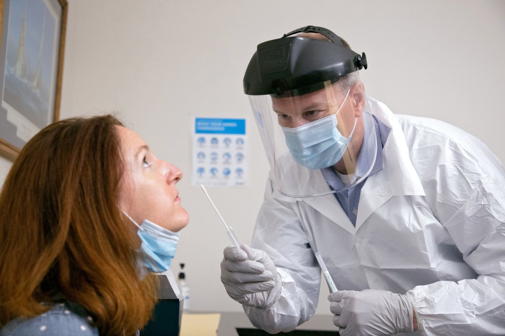 Mulher fazendo teste de antígeno com swab nasal para Covid-19