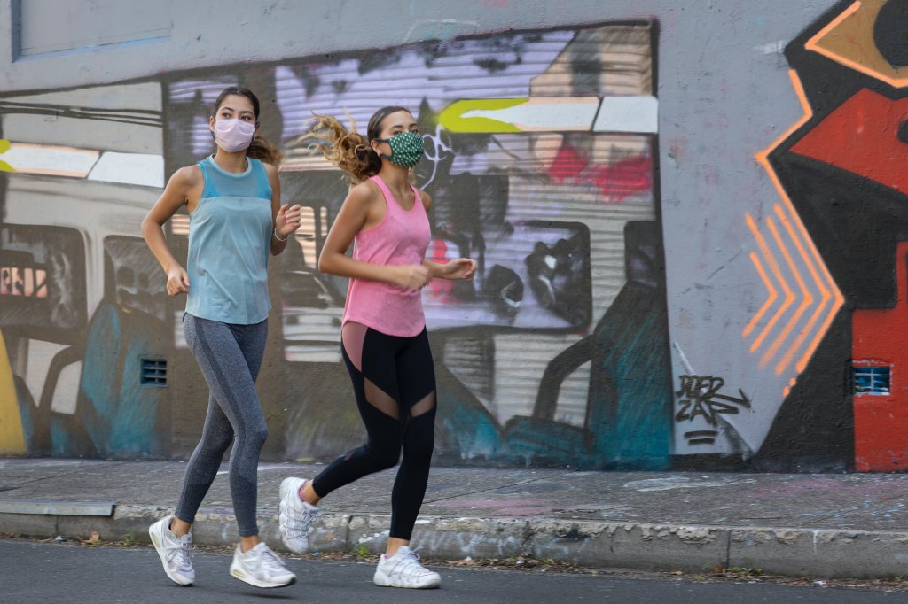 Foto de duas mulheres correndo de máscara