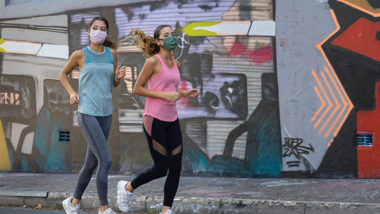Foto de duas mulheres correndo de máscara