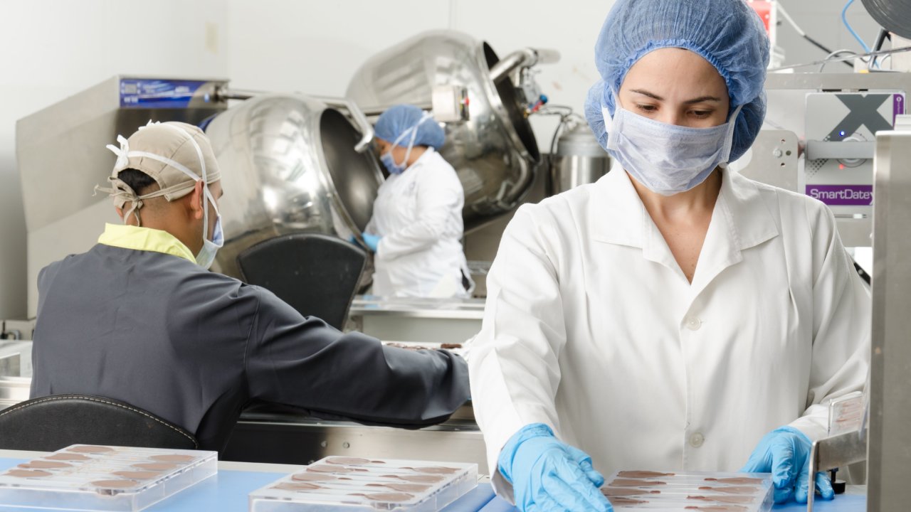foto de pessoas trabalhando trajadas e de máscara em laboratório