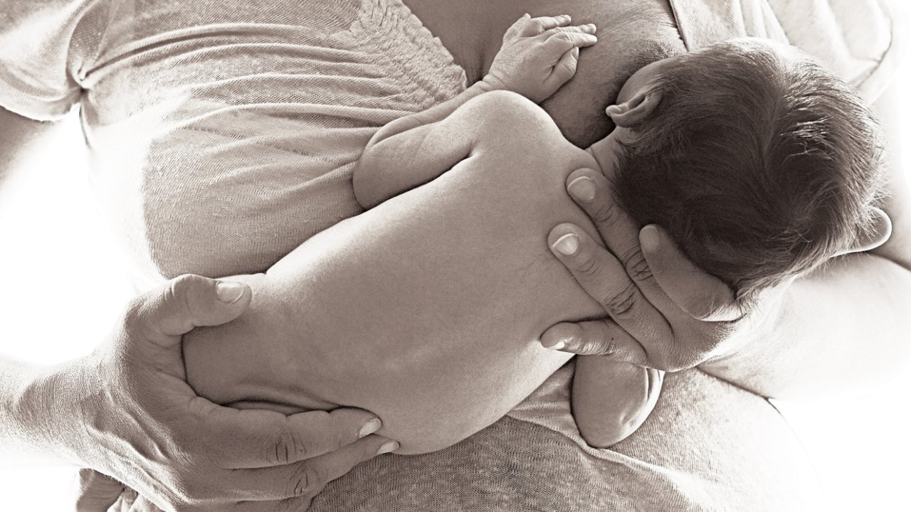 foto preto e branca de mãe amamentando bebê