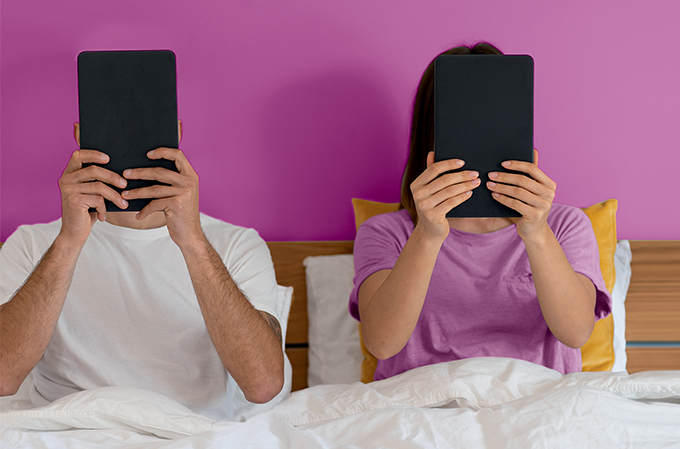 foto de casal na cama vendo cada um o seu tablet