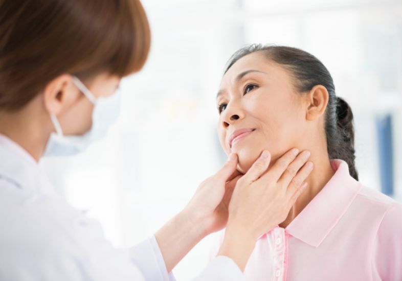 Dia da Tireoide: mulher japonesa sendo examinada no pescoço por médica de máscara