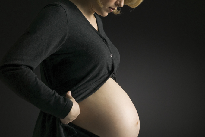 Foto de mulher grávida usando roupa preta, simbolizando o medo de contraria Covid
