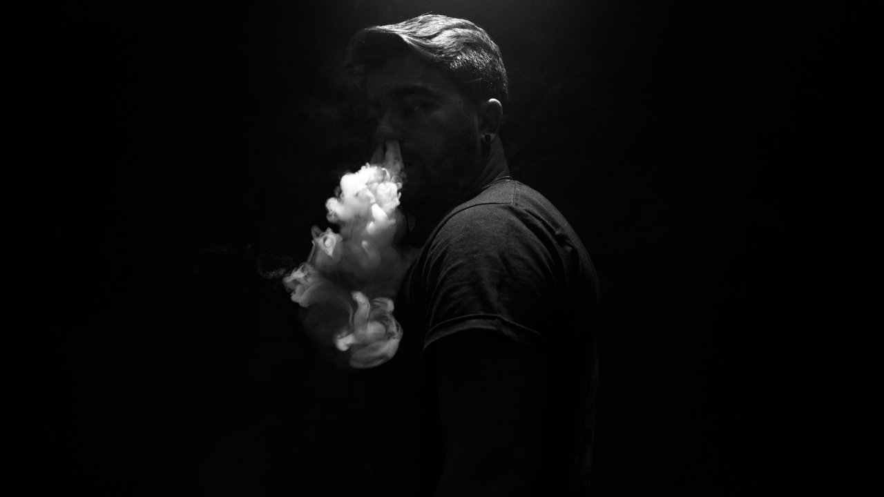 foto de homem fumando em fundo escuro