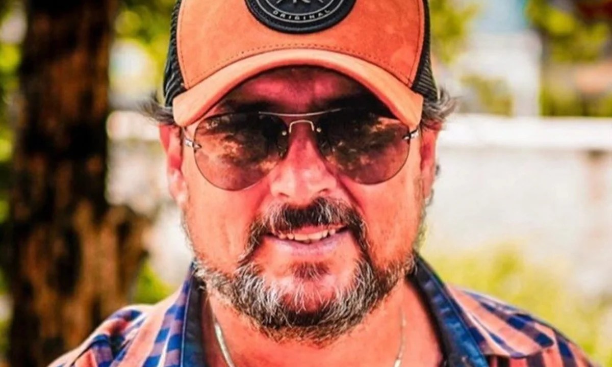 Homem de boné, óculos escuros, barba e bigode